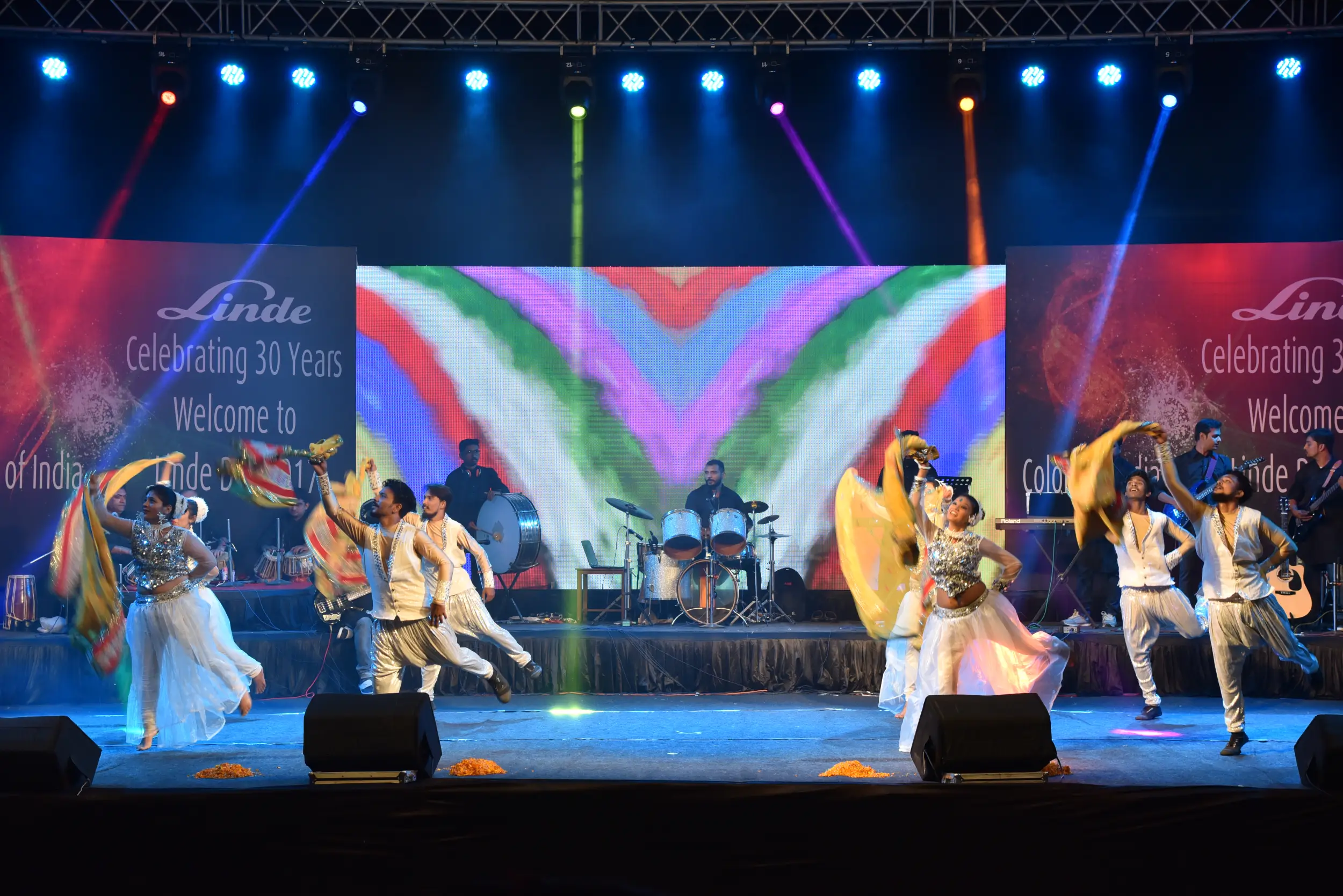 Man and woman speaking on stage at night with blue lighting